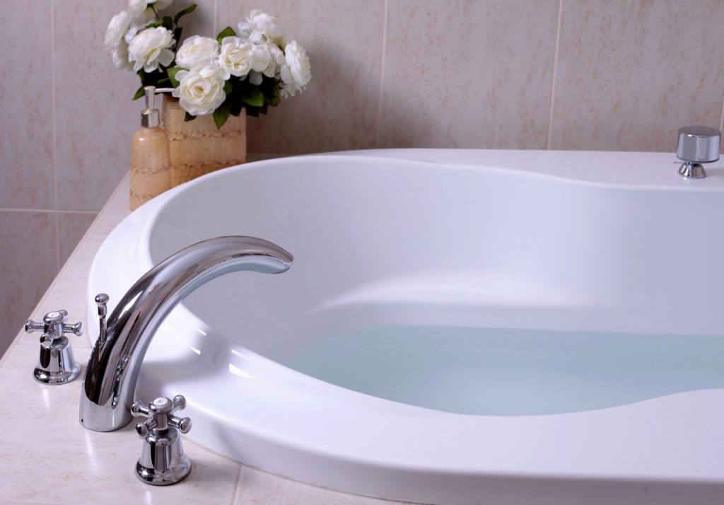 white bath tub with faucet and mozaic tiles